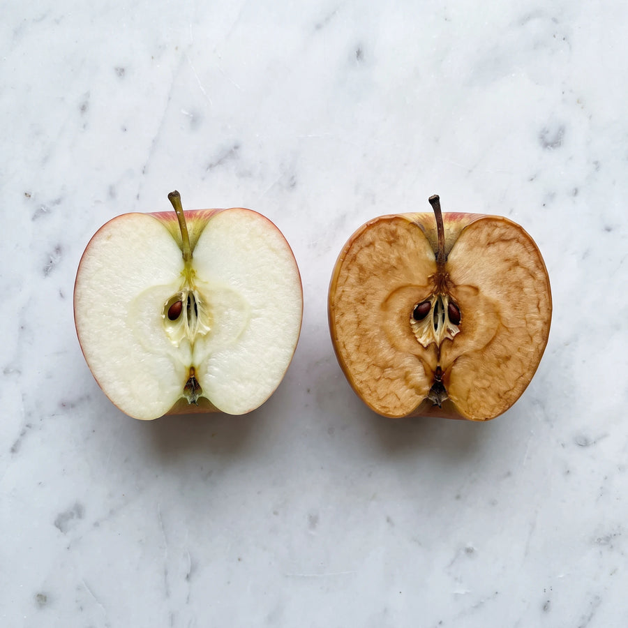 Dos mitades de manzana sobre mármol: una recién cortada y otra ya oxidada